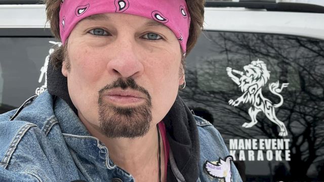 A person in a pink bandana with sunglasses poses in front of a vehicle with a logo that says "MAIN EVENT KARAOKE."